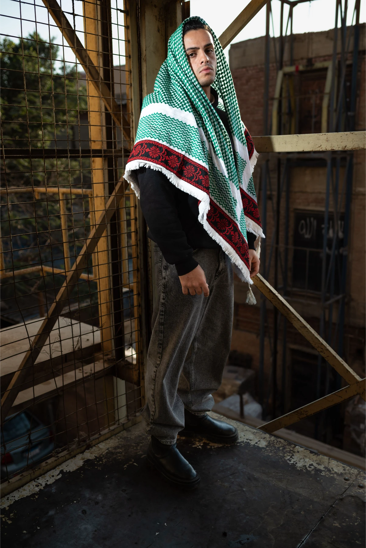 Person wearing a green and red patterned shawl in an industrial setting